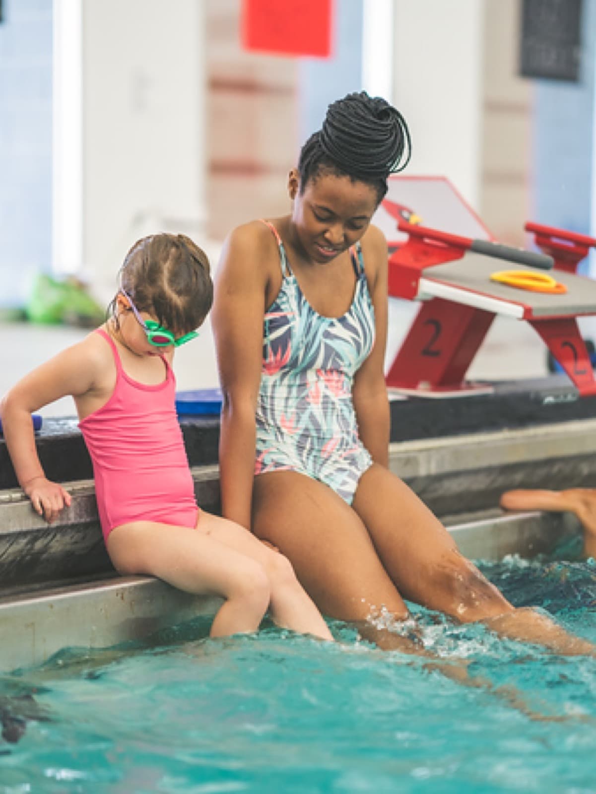 Two young swimmers sitting at the edge of the MSSD pool with their feet in the water